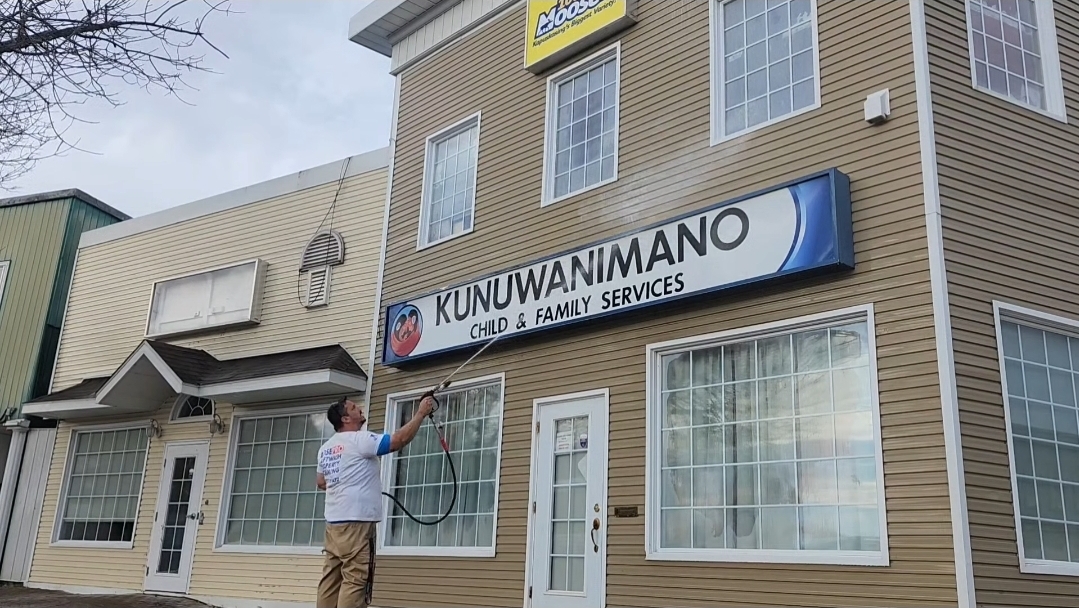 Property cleaning technician washing an exterior surface